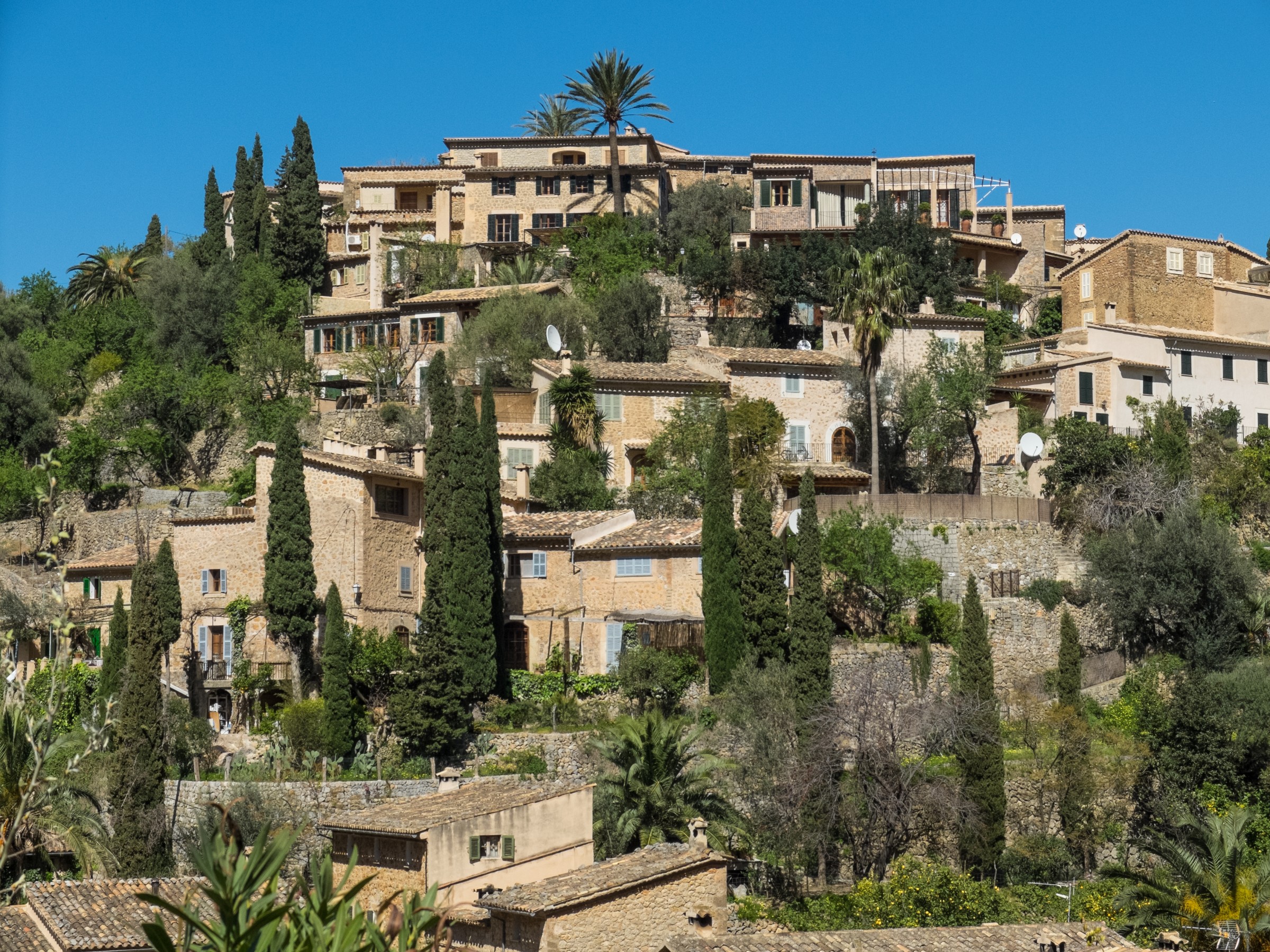 Maisons de pierre de Deià étagées sur la colline, entre cyprès et palmiers
